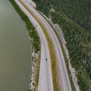 Lake Reflections - Drone shot of a winding road flanked by lush for #7054809